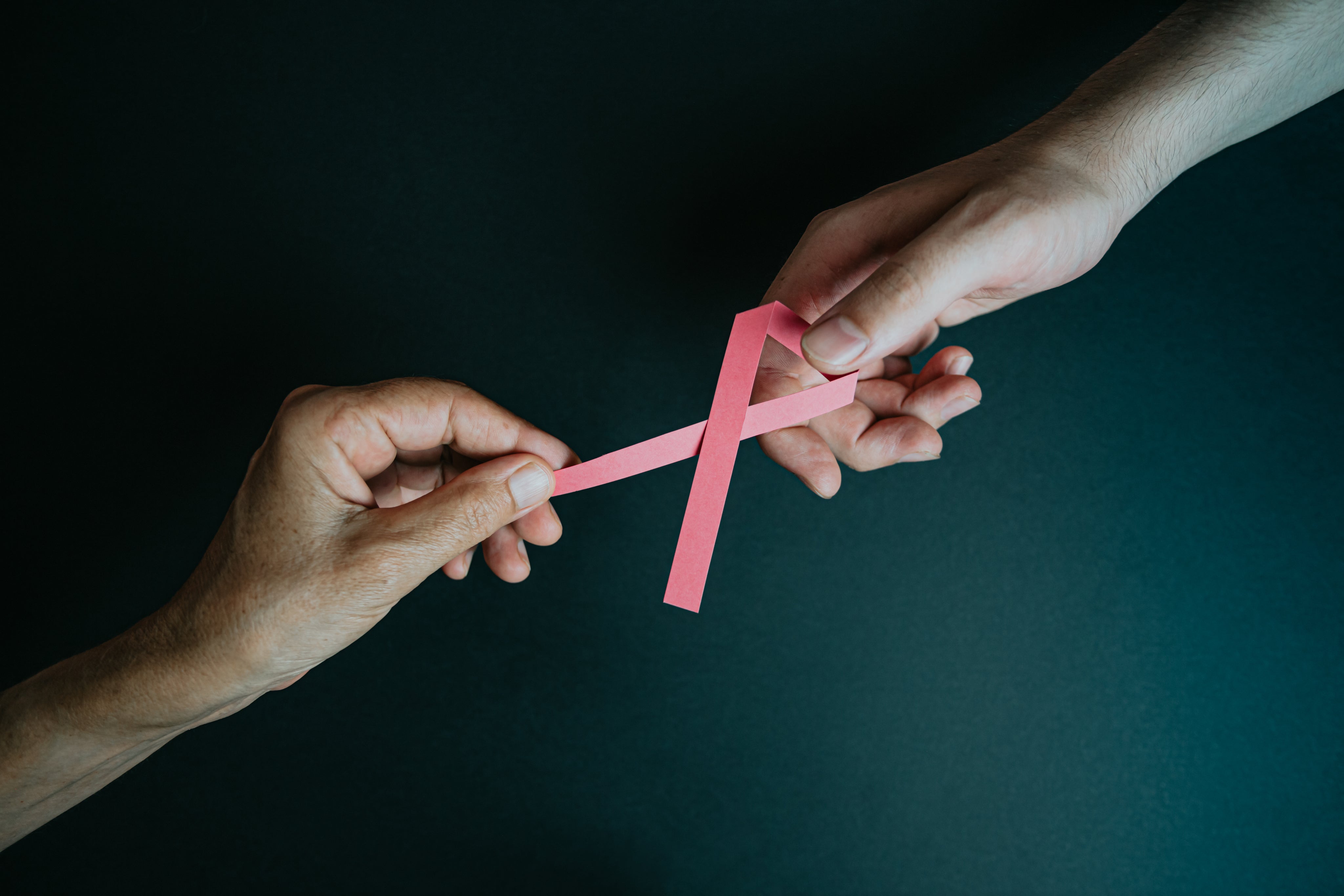 two-hands-hold-each-end-of-pink-ribbon.jpg